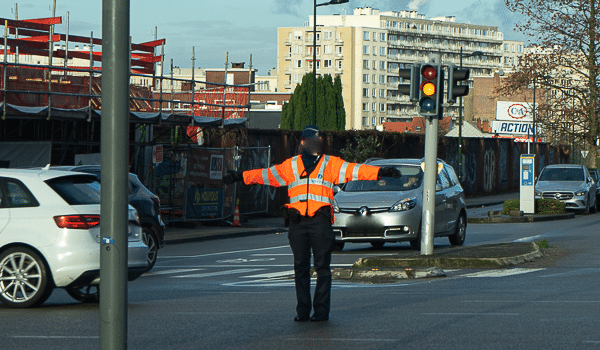L'agent se tient de face ou donne le dos avec les bras tendus horizontalement signifie qu'il faut s'arrêter